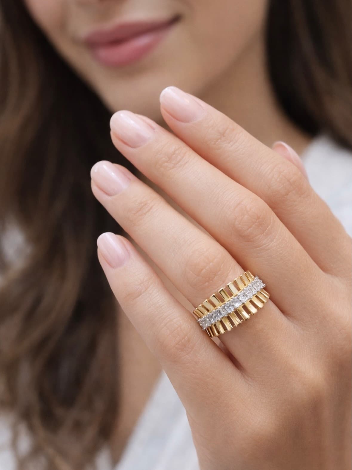 Main aux ongles nude, puis bague en or sertie d'une ligne de diamants
